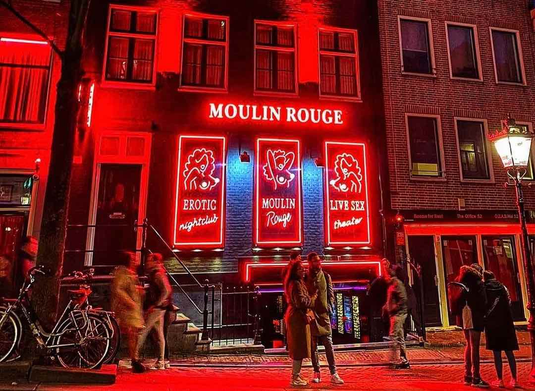 five tourists in front of Moulin Rouge in Amsterdam at night